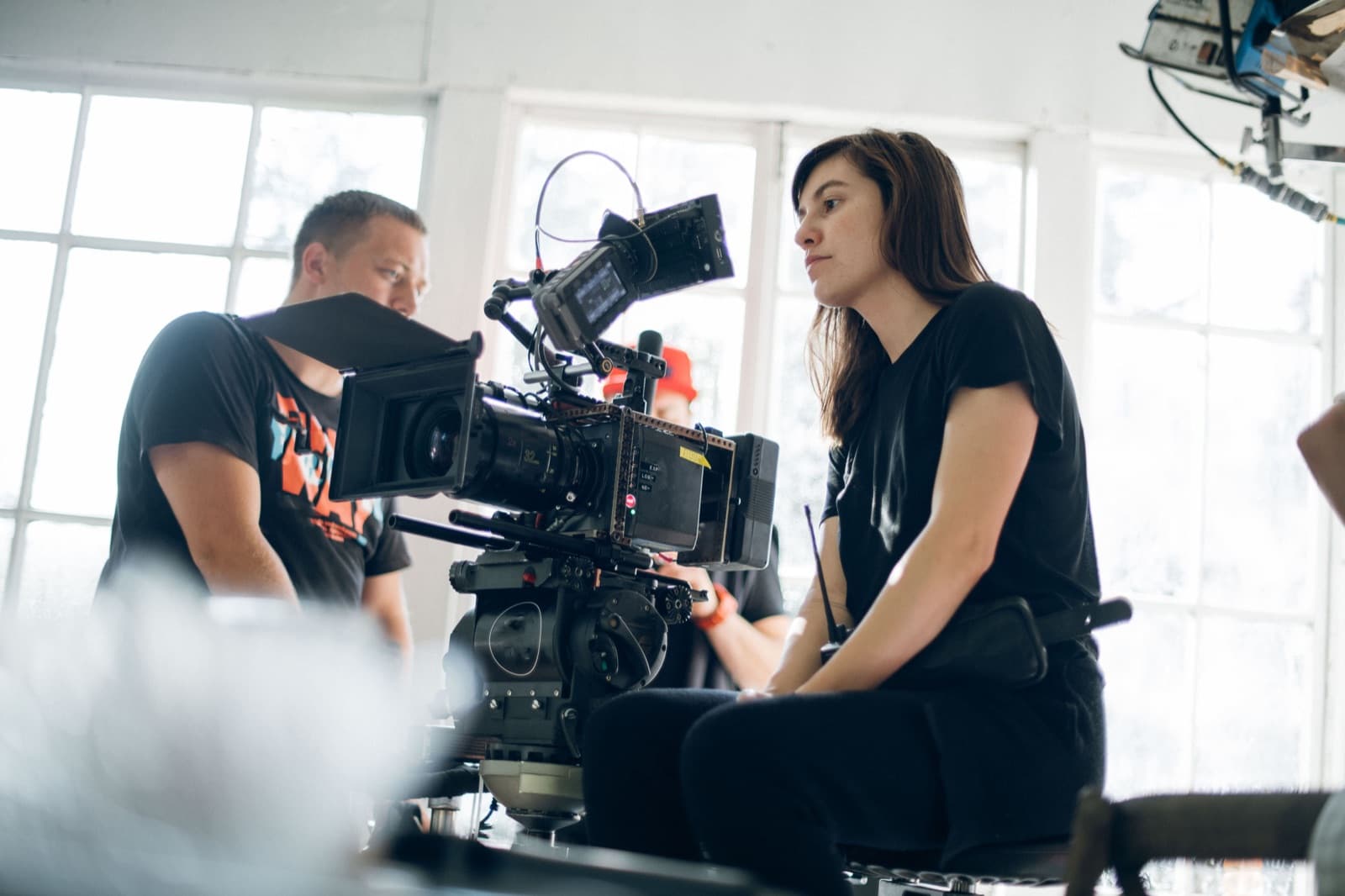 Equipe de produção de vídeo em set, diretor de fotografia e diretora operando câmera de cinema com luz natural